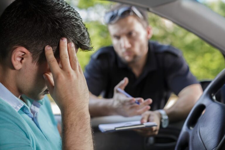 Homem com mão na cabeça enquanto o outro homem aplica uma multa de trânsito
